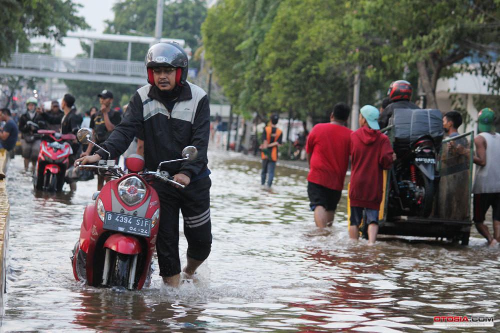 Ilustrasi pengendara skutik mendorong motor yang mogok