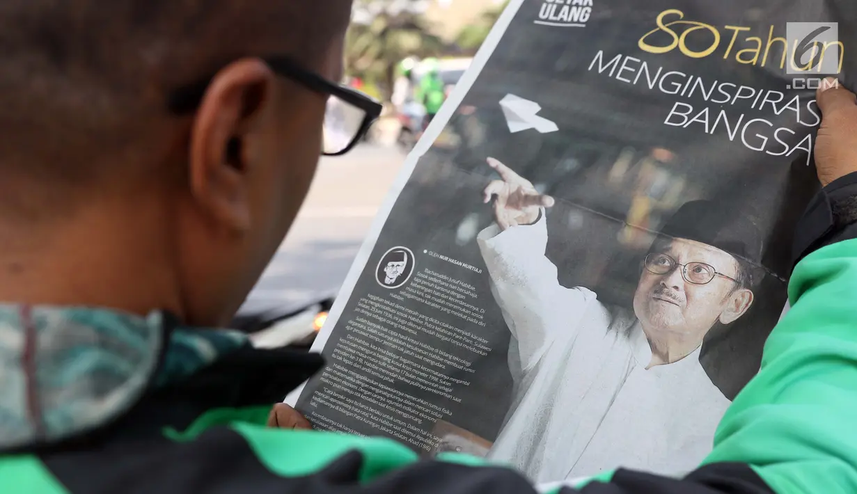 Warga membaca koran sambil menunggu di sisi jalan TMP Kalibata untuk melihat prosesi pemakaman Presiden RI ke-3 BJ Habibie, Jakarta, Kamis (12/9/2019). BJ Habibie meninggal pada Rabu (11/9/2019) pukul 18.05 WIB di usia 83 tahun. (Liputan6.com/Helmi Fithriansyah)