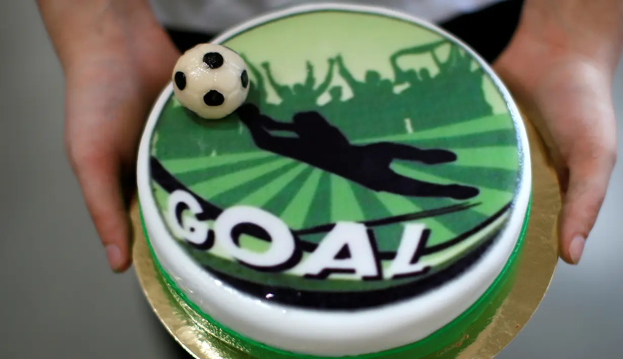 Seseorang menunjukkan kue bertema Euro 2016 yang dibuat di sebuah tempat pembuatan kue di Munich, Jerman, Senin (20/6). Beraneka kue bertema Euro 2016 mewarnai perhelatan sepakbola Eropa. (REUTERS/Michaela Rehle)