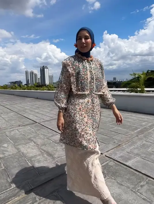 Tya Ariestya tampil mengenakan tunik dengan bordiran bunga-bunga warna pastel. Dipadukan kerudung biru dan rok putih bermotif. [@tya_ariestya]