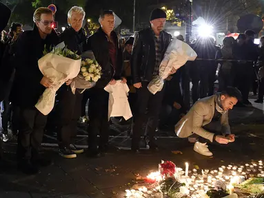 Grup band U2 Bono, Adam Clayton , Larry Mullen Jr  dan The Edge meletakkan karangan bunga di trotoar di depan gedung pertunjukan Bataclan Theatre, salah satu tempat serangan teroris di Paris, Perancis, Sabtu (14/11). (AFP PHOTO / FRANCK FIFE)
