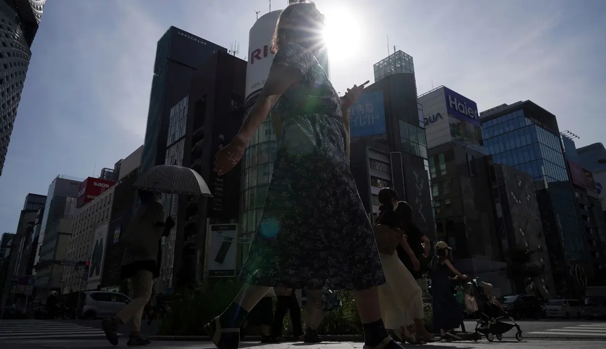 Orang-orang yang memakai masker pelindung untuk membantu mengekang penyebaran virus corona berjalan di sepanjang penyeberangan pejalan kaki, Tokyo, Jepang, 1 Agustus 2022. Cuaca panas terus berlanjut di wilayah metropolitan karena suhu diperkirakan akan meningkat hingga 35 derajat Celcius (95 derajat Fahrenheit), menurut biro meteorologi Jepang. (AP Photo/Eugene Hoshiko)