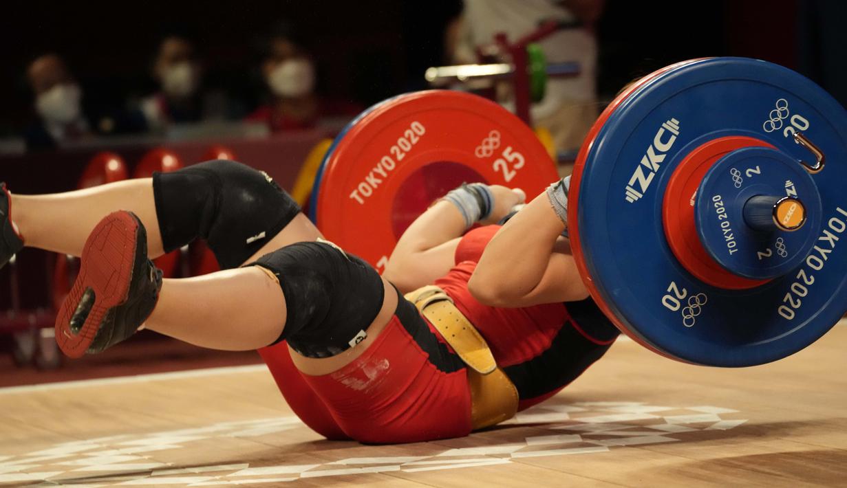 Hoang Thi Duyen dari Vietnam terjatuh saat bertanding di cabang angkat besi 59kg putri Olimpiade Tokyo 2020, Selasa (27/7/2021). (Foto: AP/Luca Bruno)