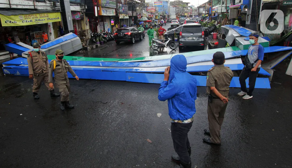 Gapura tumbang melintang di sebuah jalan di Kota Tangerang, Banten, Kamis (23/12/2021). Puluhan pohon dan gapura tumbang akibat terjangan angin kencang saat hujan lebat melanda Kota Tangerang. (Liputan6.com/Angga Yuniar)
