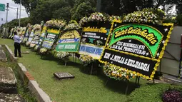 Warga mengambil gambar karangan bunga ucapan duka cita untuk Probosutedjo yang memenuhi Jalan Diponegoro, Jakarta, Senin (26/3). Probosutedjo meninggal dunia pada usia 87 tahun. (Liputan6.com/Arya Manggala)