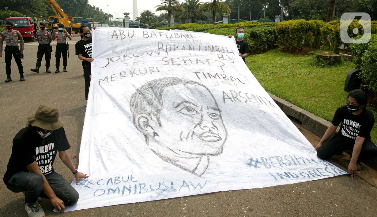 Sejumlah aktivis melakukan aksi simbolik di kawasan Patung Kuda, Jakarta, Kamis (18/3/2021). Aktivis menuntut Presiden Joko Widodo untuk mencabut Omnibus Law UU Cipta Kerja dan regulasi turunannya yang menghapus Fly Ash Bottom Ash (FABA) dari daftar limbah B3. (Liputan6.com/Faizal Fanani)