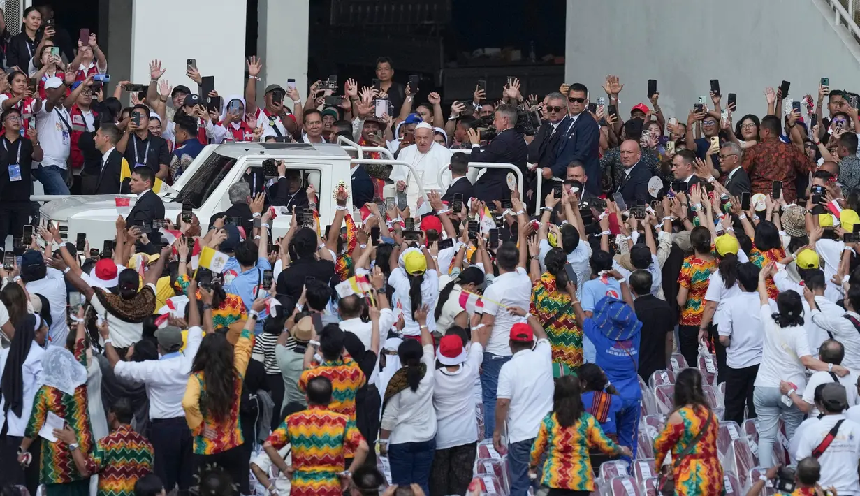 Terlihat, Paus Fransiskus memberkati umat Katolik yang memadati stadion dengan membuat tanda salib. (Dita ALANGKARA/POOL/AFP)