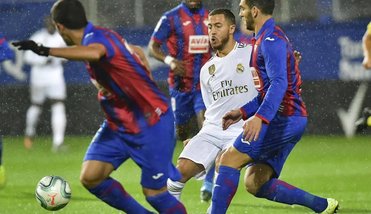 Gelandang Real Madrid, Eden Hazard mengumpan bola dari kawalan dua pemain Eibar pada pertandingan lanjutan Liga Spanyol di  stadion Ipurua (9/11/2019). Real Madrid menang telak 4-0 atas Eibar. (AP Photo/Alvaro Barrientos)