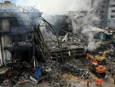 Petugas penyelamat mencari korban di antara puing-puing setelah kebakaran besar di sebuah pusat perbelanjaan di Karachi pada Senin 19 Januari 2026. Tim pencari dan penyelamat di Karachi, Pakistan, masih berjuang melakukan pencarian korban di reruntuhan sebuah gedung pusat perbelanjaan. (Asif HASSAN/AFP)