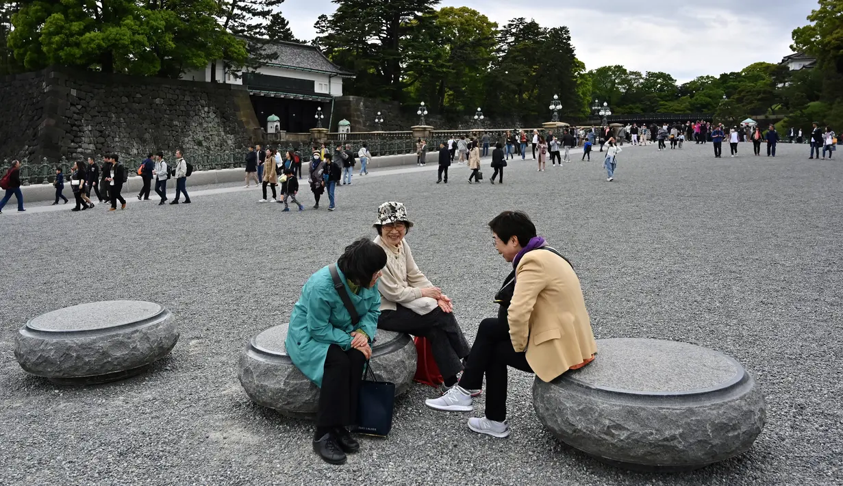 Masyarakat mengobrol dan luar halaman Istana Kekaisaran di Tokyo, Jepang (29/4/2019). Kaisar Jepang Akihito akan turun dari Tahta Krisan pada 30 April 2019 mengakhiri 30 tahun masa pemerintahannya. (Charly Triballeau / AFP)