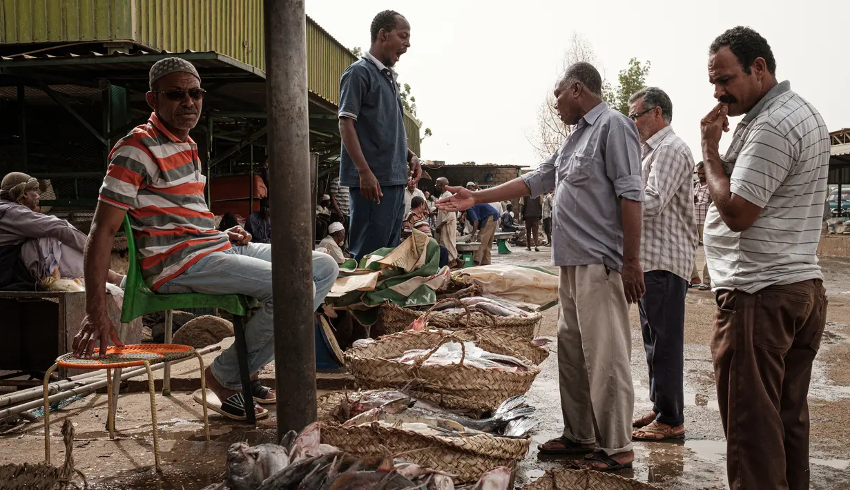 Pembeli bernegosiasi sebelum membeli ikan di sebuah pasar ikan di dekat Sungai Nil, di kota kembar Khartoum, Omdurman (24/6/2019). Khartoum didirikan pada tahun 1821 sebagai pos militer Mesir, namun berkembang menjadi pusat perdagangan regional. (AFP Photo/Yasuyoshi Chiba)