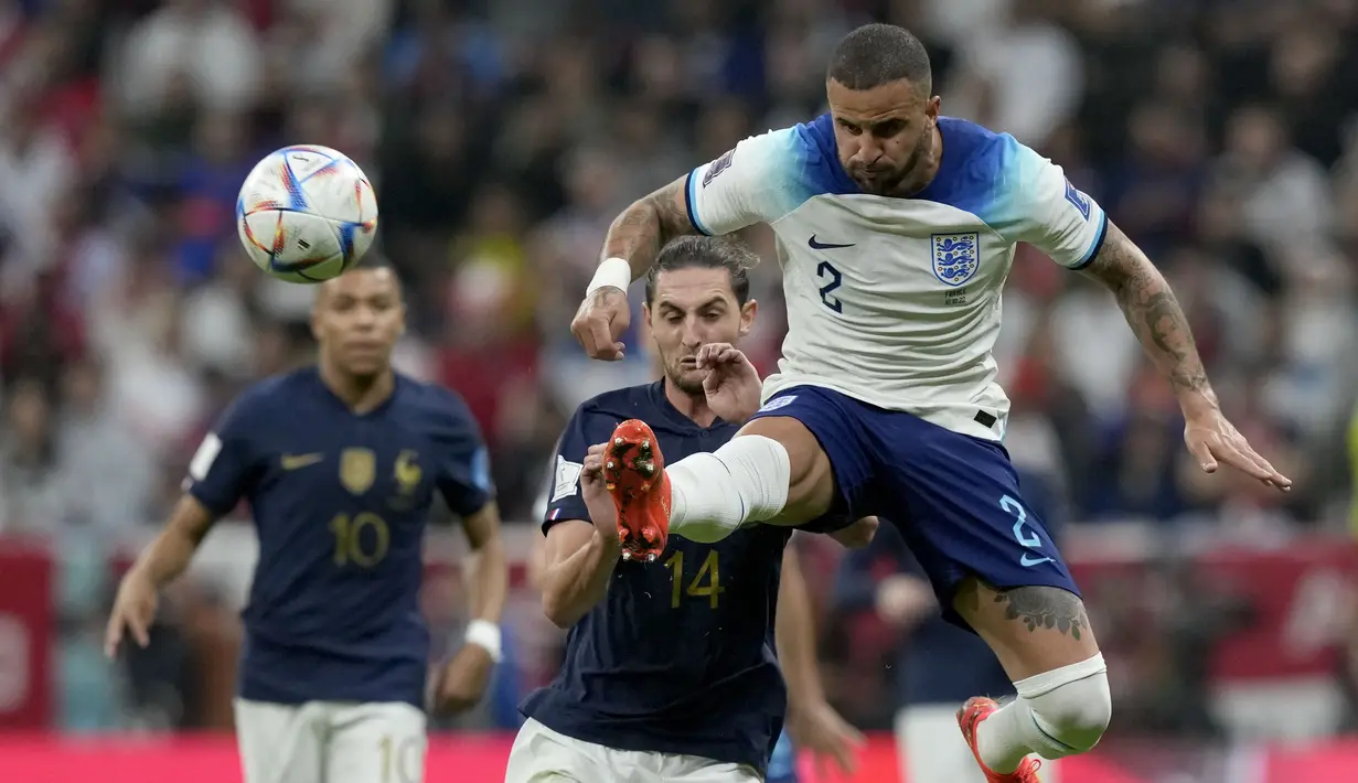 Bek Inggris Kyle Walker melompat untuk merebut bola di samping pemain Prancis Adrien Rabiot dan Kylian Mbappe pada perempat final Piala Dunia 2022 di Al Bayt Stadium, Al Khor, Minggu (11/12/2022) dini hari WIB. Laga Inggris vs Prancis yang baru selesai digelar, dimenangkan Prancis dengan skor 2-1. (AP Photo/Frank Augstein)