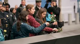 Kerabat meletakkan mawar di atas plakat bertuliskan nama-nama korban pengeboman World Trade Center 1993 pada upacara peringatan “Tragedi 9/11” di New York, Rabu (26/2/2020). 27 tahun lalu teroris meledakkan bom di sebuah garasi parkir WTC yang menewaskan enam korban. (Scott Heins/Getty Images/AFP)