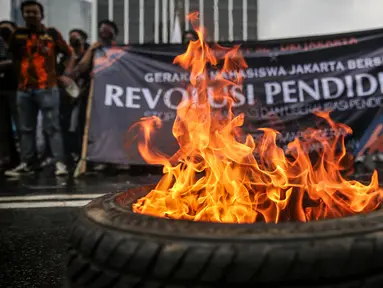 Massa yang tergabung dalam Gerakan Mahasiswa Jakarta Bersatu membakar ban saat unjuk rasa di depan gedung Kementerian Pendidikan dan Kebudayaan, Jakarta, Kamis (2/7/2020). Mereka menuntut adanya keringanan uang tunggal kuliah (UKT) sebesar 50 persen di tengah pandemi. (Liputan6.com/Faizal Fanani)