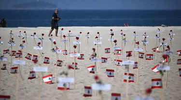 Seorang pria berjalan melewati 245 mawar yang ditempatkan oleh LSM Rio da Paz beserta nama korban dan bendera Lebanon untuk memperingati 3 tahun sejak ledakan Beirut 2020 di Pantai Copacabana, Rio de Janeiro, Brasil, diambil pada 4 Agustus 2023. (AFP/Carl De Souza)