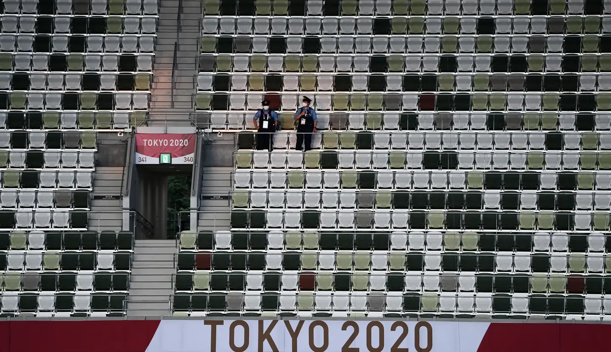 Polisi berdiri di tribun yang kosong sebelum upacara pembukaan Olimpiade Tokyo 2020 di Stadion Olimpiade, Tokyo, Jepang, Jumat (23/72021).  Upacara pembukaan Olimpiade Tokyo 2020 akan digelar pada 23 Juli 2021 malam. (Jewel SAMAD/AFP)