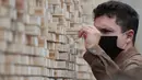 Seorang pria mengambil sebuah balok kayu dari "The Disappearing Wall" di Grand Place, Brussel, Belgia, 3 Oktober 2020. Instalasi seni memperingati 30 tahun reunifikasi Jerman itu terdiri dari 6.000 balok kayu dilengkapi kutipan para seniman dan pemikir dari seluruh dunia. (Xinhua/Zheng Huansong)