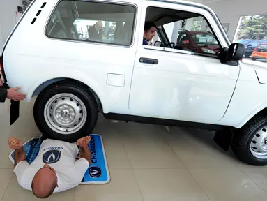 Seorang pengendara mobil melindas tubuh Norik Yajian pada sebuah atraksi di Tbilisi, Georgia, Selasa (16/2). Atraksi ini nekat dilakukan Norik untuk memecahkan rekor Guinness. (AFP PHOTO/Vano SHLAMOV)