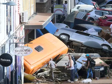 Para pejalan kaki berdiri di samping mobil-mobil yang tertimbun setelah banjir yang mematikan di Sedavi, selatan Valencia, Spanyol timur, pada tanggal 30 Oktober 2024. (Jose Jordan/AFP)