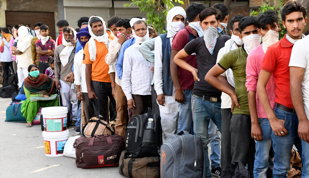 Pekerja migran yang terdampar dan keluarga mereka berkumpul menunggu pemeriksaan medis sebelum pergi dengan kereta api untuk kembali ke kota asal mereka ke Jaunpur, negara bagian Uttar Pradesh, setelah pemerintah melonggarkan lockdown di Amritsar, India, Selasa (19/5/2020). (NARINDER NANU/AFP)