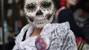 Seorang wanita berpakaian seperti "Catrina" ambil bagian dalam parade Hari Orang Mati di Reforma Avenue, Mexico City, 21 Oktober 2018. Hari kematian ini merupakan tradisi Halloween ala warga Hispanik di Meksiko. (RODRIGO ARANGUA/AFP)