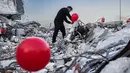 Ogun Sever Okur, pria Turki berusia 38 tahun menggantung balon di atas puing-puing bangunan yang runtuh di Antakya, Turki selatan pada 21 Februari 2023, menyusul gempa berkekuatan 6,4 yang melanda pada 20 Februari, dua minggu setelah gempa berkekuatan 7,8 gempa berkekuatan besar melanda dekat Gaziantep dan telah menewaskan lebih dari 44.000 orang. (AFP/Sameer Al-Doumy)