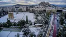 Bukit Acropolis kuno (belakang) dan kuil Zeus (depan) tertutup salju setelah hujan salju lebat di Athena, Yunani, Rabu (17/2/2021). Kota Athena yang mendadak berselimut salju tebal membuat Acropolis menjadi putih bak pemandangan di kartu ucapan. (Antonis Nikolopoulos/Eurokinissi via AP)