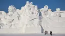 Orang-orang berjalan di samping patung salju raksasa di Pameran Seni Patung Salju Internasional Harbin Sun Island di Harbin, di provinsi Heilongjiang timur laut Tiongkok pada 4 Januari 2023, menjelang Festival Es dan Salju Internasional Harbin Tiongkok ke-39. (AFP/Hector Retamal)