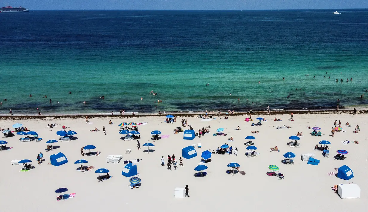 Pandangan udara menunjukkan orang-orang berada di atas pasir Miami Beach di Florida, Rabu (10/6/2020). Pantai Miami dibuka hari ini untuk pertama kalinya setelah hampir tiga bulan ditutup guna menekan jumlah penyebaran corona Covid-19. (CHANDAN KHANNA / AFP)