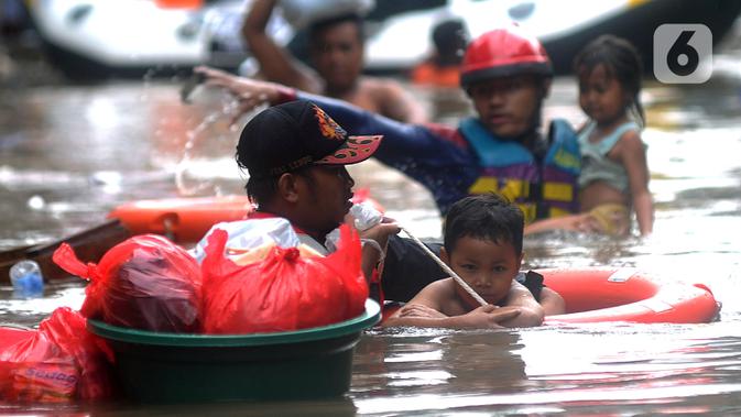 Petugas Pemadam Kebakaran mengevakuasi anak-anak korban banjir dengan menggunakan ban di kawasan Karet Pasar Baru Barat, Jakarta, Selasa (25/2/2020). Banjir yang terjadi sejak subuh akibat luapan Kanal Banjir Barat tersebut merendam ratusan rumah hingga setinggi dua meter. (merdeka.com/Arie Basuki)