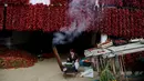Warga memasak di depan rumahnya yang penuh dengan paprika merah yang digantung pada tembok untuk dikeringkan, di Desa Donja Lakosnica, Serbia, 6 Oktober 2016. Saat musim panen, warga menjemur paprika di dinding hingga atap rumah. (REUTERS/Marko Djurica)