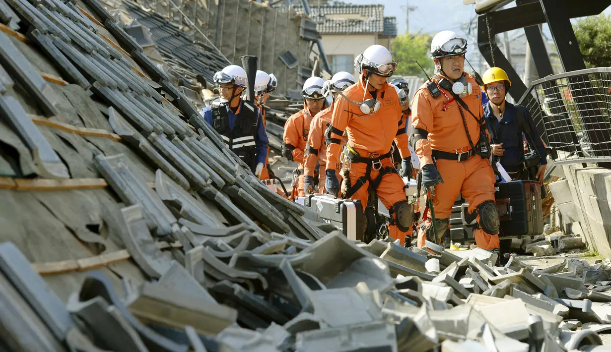 Petugas pemadam berjalan di antara reruntuhan rumah yang hancur akibat gempa di kota Mashiki, Prefektur Kumamoto, Jepang bagian selatan, Kamis (14/4). Gempa berkekuatan 6,4 SR itu menewaskan sembilan orang dan melukai 760 lainnya. (REUTERS/Kyodo)