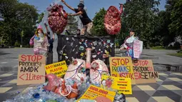 Aktivis dari Ecological Observation and Wetlands Conservation (ECOTON) dan mahasiswa memasang instalasi berbentuk jantung dan paru-paru yang rusak akibat terpapar sampah mikroplastik dalam sebuah protes untuk meningkatkan kesadaran akan dampak plastik sekali pakai terhadap lingkungan dan kesehatan manusia di Surabaya, Rabu 16 Juli 2025. (Juni KRISWANTO/AFP)