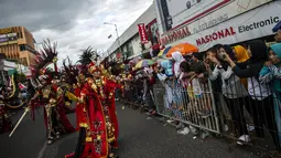 Warga menyaksikan peserta menampilkan kreasi kostum dalam Jember Fashion Carnaval (JFC) di Jember, Provinsi Jawa Timur pada Minggu (4/8/2019). Kegiatan ini mengangkat tema 'tribal grandeur', dengan menghadirkan keagungan 8 suku di dunia. (Photo by JUNI KRISWANTO / AFP)