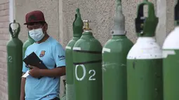 Seorang pria menunggu di dekat tabung oksigennya yang kosong dalam antrean di luar toko untuk mengisi ulang di tengah pandemi COVID-19 di kawasan kumuh Villa El Salvador di Lima, Peru, Kamis (21/1/2021). Toko dibatasi untuk mengisi ulang hanya 20 tabung oksigen dalam sehari. (AP Photo/Martin Mejia)