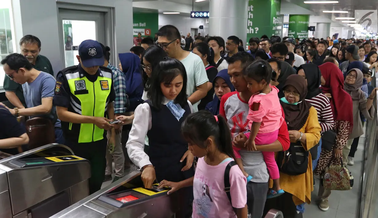 Petugas membantu penumpang melakukan tap kartu saat akan menggunakan layanan transportasi Moda Raya Terpadu (MRT) pada libur lebaran 2019 di Stasiun MRT Bundaran HI, Jakarta, Kamis (6/6/2019). Meski sudah berbayar, masyarakat tetap antusias mencoba MRT di libur Idul Fitri. (Liputan6.com/Johan Tallo)
