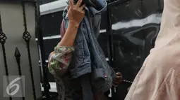 Keluarga Gatot Brajamusti menutupi wajahnya dengan jaket di kawasan Pondok Pinang, Jakarta, Selasa (30/8).  Gatot ditangkap oleh Satuan Narkoba Polres Mataram dan Lombok Barat pada Minggu (28/8) atas kepemilikan narkoba. (Liputan6.com/Herman Zakharia)