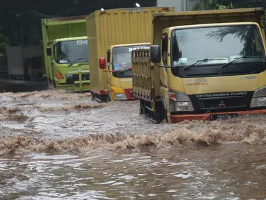 Sejumlah truk melewati banjir yang merendam terowongan di Cawang, Jakarta, Jumat (19/2/2021). Hujan yang turun sejak semalam membuat sejumlah jalanan di Ibu Kota tergenang banjir dengan ketinggian sekitar 30-50 cm. (merdeka.com/Imam Buhori)