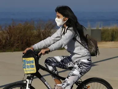 Seorang anak perempuan yang memakai masker menaiki sepeda di Beirut, ibu kota Lebanon (26/12/2020). Menteri Kesehatan Lebanon Hamad Hassan pada Jumat (25/12) mengumumkan bahwa seorang penumpang yang tiba di Beirut dari Inggris membawa varian baru COVID-19. (Xinhua/Bilal Jawich)
