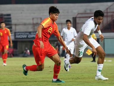 Striker China U-19, Tayier Xiaokaitijiang, berebut bola dengan striker Timnas Indonesia U-19, Serdy Ephy Fano Boky, pada laga ujicoba di Stadion I Wayab Dipta, Bali, Minggu (20/10). Indonesia kalah 1-3 dari China. (Bola.com/Aditya Wany)