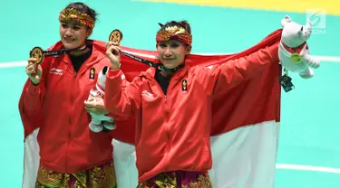 Pasangan pesilat Indonesia, Ayu Sidan Wilantari dan Ni Made Dwiyanti membentangkan bendera merah putih saat merayakan kemenangan usai meraih medali emas nomor seni ganda putri di Padepokan Pencak Silat (TMII, Rabu (29/8). (Merdeka.com/ Imam Buhori)