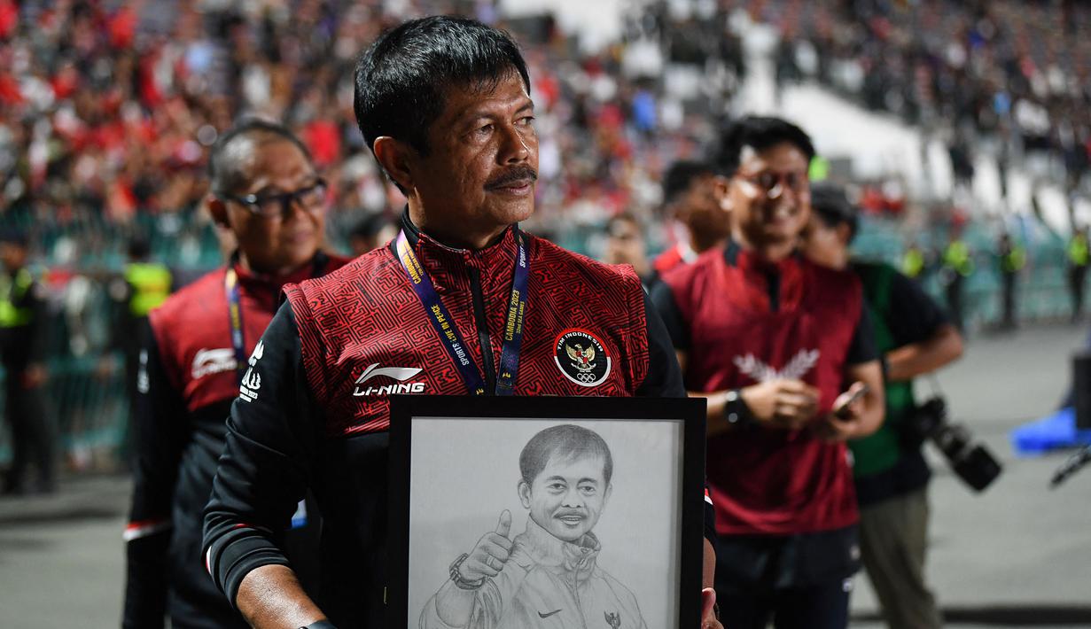 Pelatih kepala Timnas Indonesia U-22, Indra Sjafri memegang gambar dirinya saat merayakan kemenangan pada laga final sepak bola SEA Games 2023 melawan Thailand di Olympic Stadium, Phnom Penh, Kamboja, Selasa (16/05/2023). Skuad Garuda Nusantara menang dengan skor 5-2. (AFP/Nhac Ngyuen)