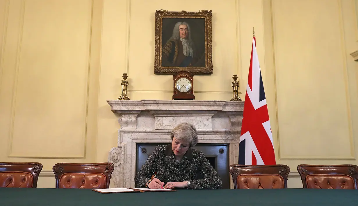 Perdana Menteri Inggris, Theresa May menandatangani surat cerai Brexit (pemisahan Inggris dari Uni Eropa) yang akan diajukan kepada Presiden Uni Eropa Donald Tusk di 10 Downing Street, London, Selasa (28/3). (Christopher Furlong/Pool Photo via AP)