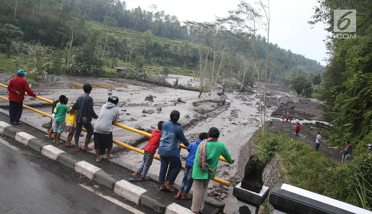 Warga berdiri di jembatan menyaksikan aliran lahar dingin yang melintasi Sungai Yeh Sah di Karangasem, Bali, Sabtu (2/12). Banjir lahar dingin ini juga mengundang pengendara yang melintas untuk berfoto dan melihat-lihat. (Liputan6.com/Immanuel Antonius)
