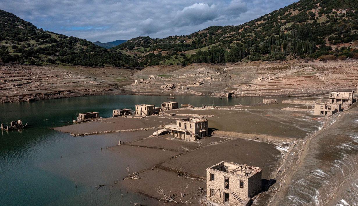 Foto ini menunjukkan sisa-sisa rumah yang muncul kembali ketika permukaan danau buatan Mornos menurun akibat kekeringan, di desa Kallio, sekitar 240 km barat laut Athena, Yunani pada 3 November 2025. Situasi ini memicu kekhawatiran akan potensi kekurangan air di kota tersebut. (Angelos TZORTZINIS/AFP)