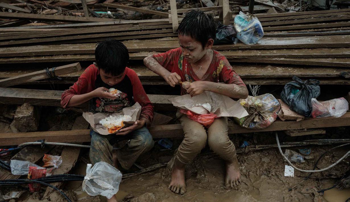 Anak-anak memakan makanan yang dibagikan di Babo, Aceh Tamiang, pada Senin 15 Desember 2025. Ancaman gangguan kesehatan menghantui anak-anak korban bencana banjir bandang dan tanah longsor yang terjadi di berbagai wilayah di Aceh, Sumatera Utara, dan Sumatera Barat. (Yasuyoshi CHIBA/AFP)