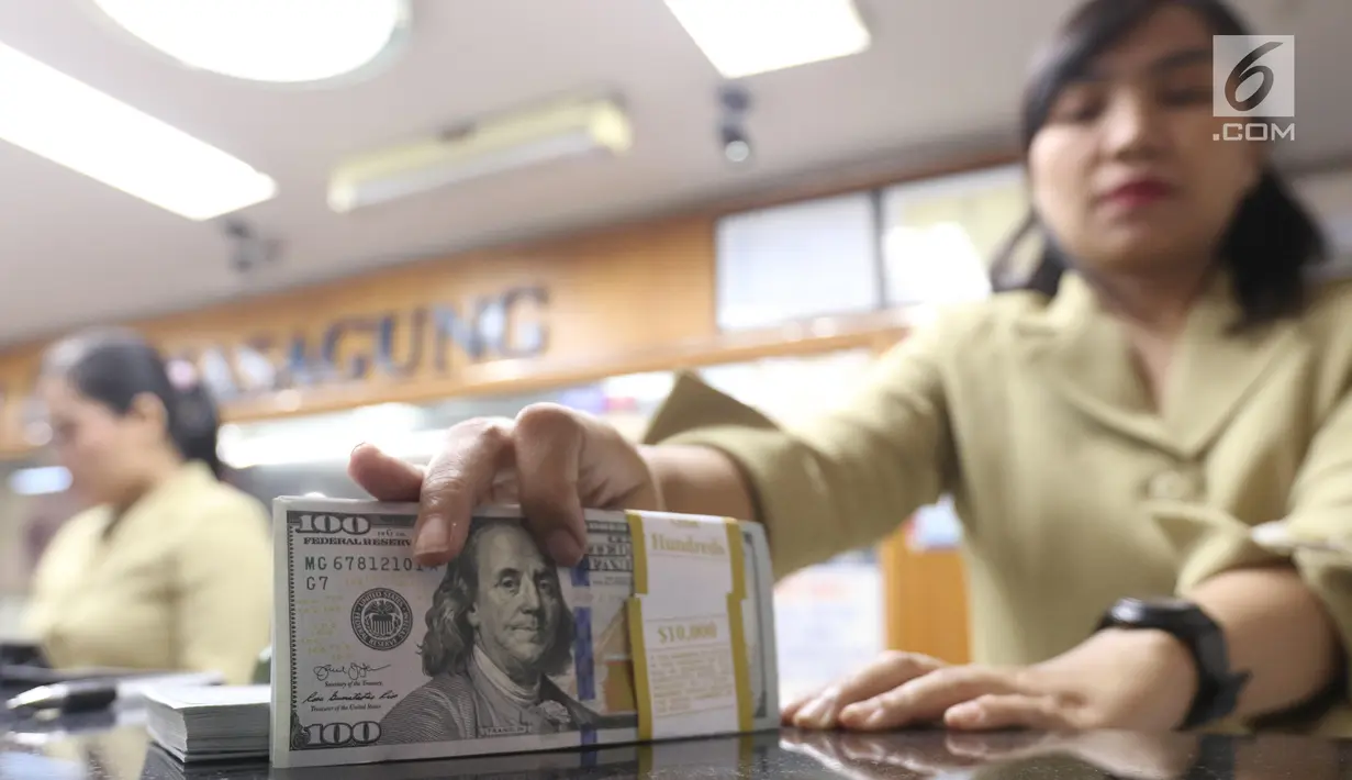 Pekerja menunjukan Dolar AS di jasa penukaran uang asing di Jakarta, Rabu (19/6/2019). Nilai tukar rupiah terhadap Dolar AS sore ini Rabu (19/6) ditutup menguat sebesar Rp 14.269 per dolar AS atau menguat 56,0 poin (0,39 persen) dari penutupan sebelumnya. (Liputan6.com/Angga Yuniar)