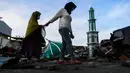 Dua wanita yang terkena dampak gempa berjalan melewati Masjid Raya Baiturrahman yang runtuh di Palu, Sulawesi Tengah, Rabu (3/10). Meski kubah dan beberapa dinding masjid runtuh, namun menaranya masih kokoh berdiri. (AFP PHOTO / JEWEL SAMAD)