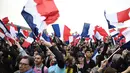 Pendukung mengibarkan bendera Prancis saat merayakan kemenangan Emmanuel Macron di luar museum Louvre, Paris, Minggu (7/5). Berdasarkan exit poll sejauh ini, rakyat Prancis memilih Macron sebagai presiden mereka yang baru. (AFP PHOTO/Eric FEFERBERG)