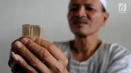Kyai Tubagus Muhammad Tamyiz mengaji dengan  Al Quran mini bertinta emas saat mengajar  para santri  memaknai Kitab Kuning' di Pondok Pesantren Almiizan, Kabupaten Bogor, Jawa Barat, Senin, (20/5/2019). Al Quran mini ini berukuran 10 mm x 10 mm. (merdeka.com/Arie Basuki)